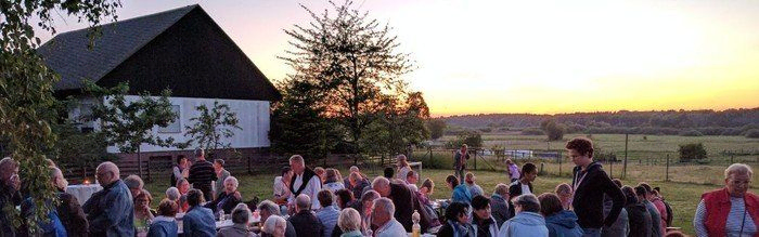 Menschen sitzen bei Abendrot im Pfarrgarten Lübars